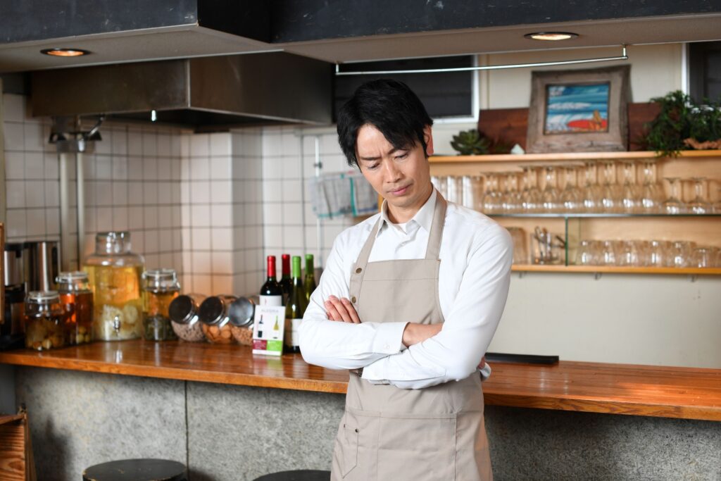 飲食店（レストラン）で悩むエプロン姿の男性